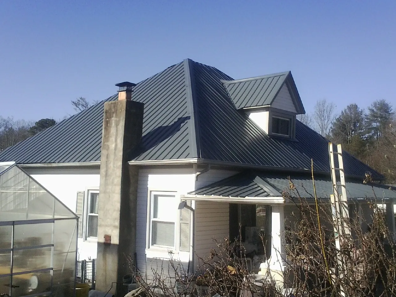 Dark blue standing seam metal roof on a white farmhouse with dormer — Slate & Tile Roof Repair by Roofing Brothers in Ayr
