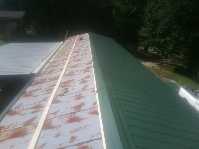 Old rusted panels beside newly installed green metal roofing — Wind Damage Roof Repair by Roofing Brothers in Ayr