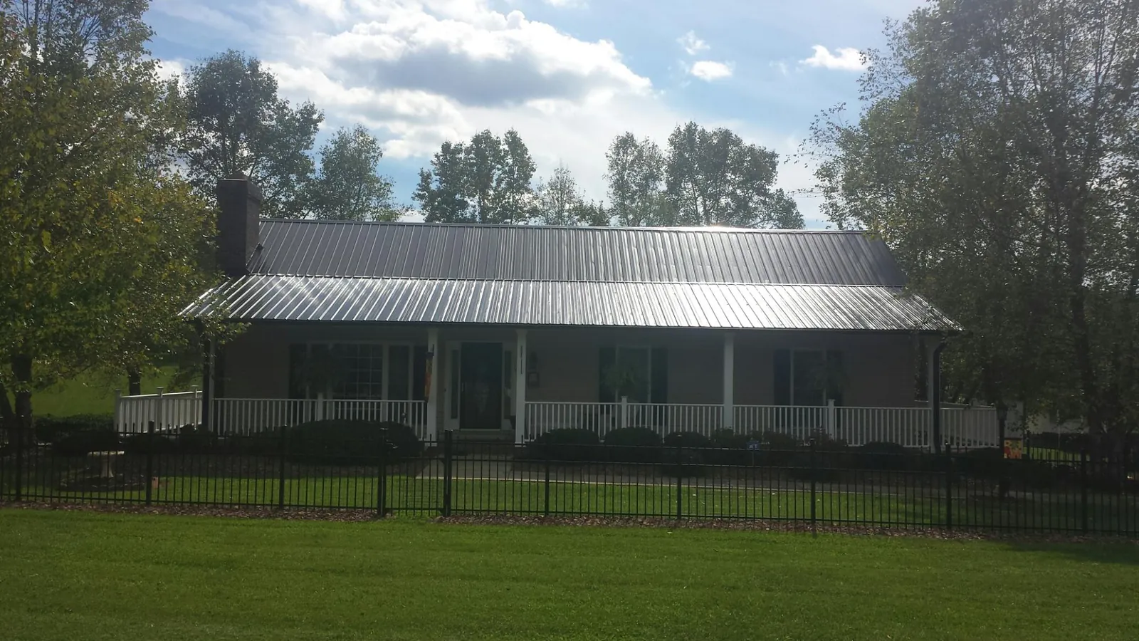 Gray metal roof on a brick ranch with a full width front porch — Gutter Guard Installation work by our crew in Ayr