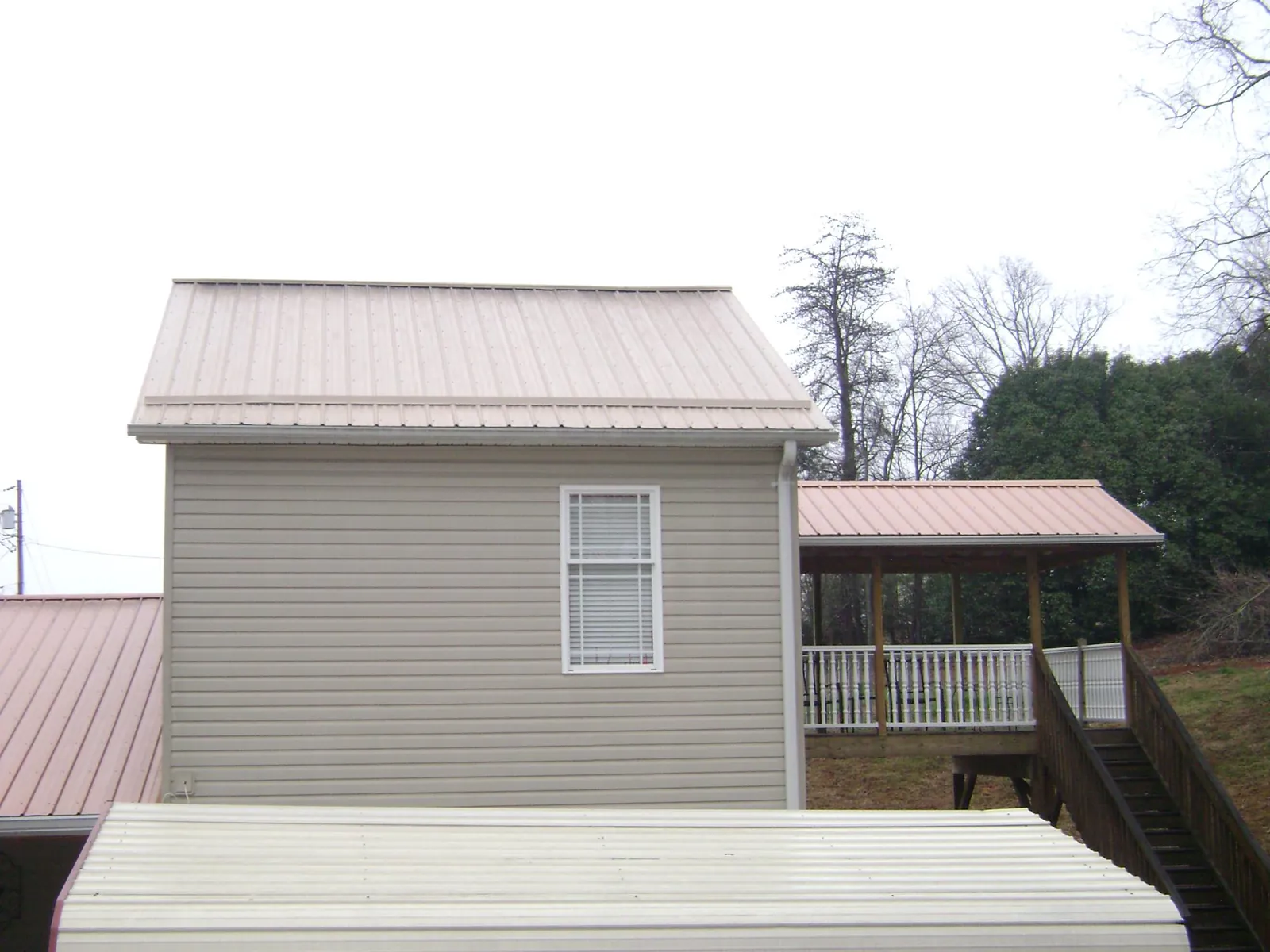 Tan metal roofs on a two story addition and attached porch, from a Roof Replacement job in Ayr